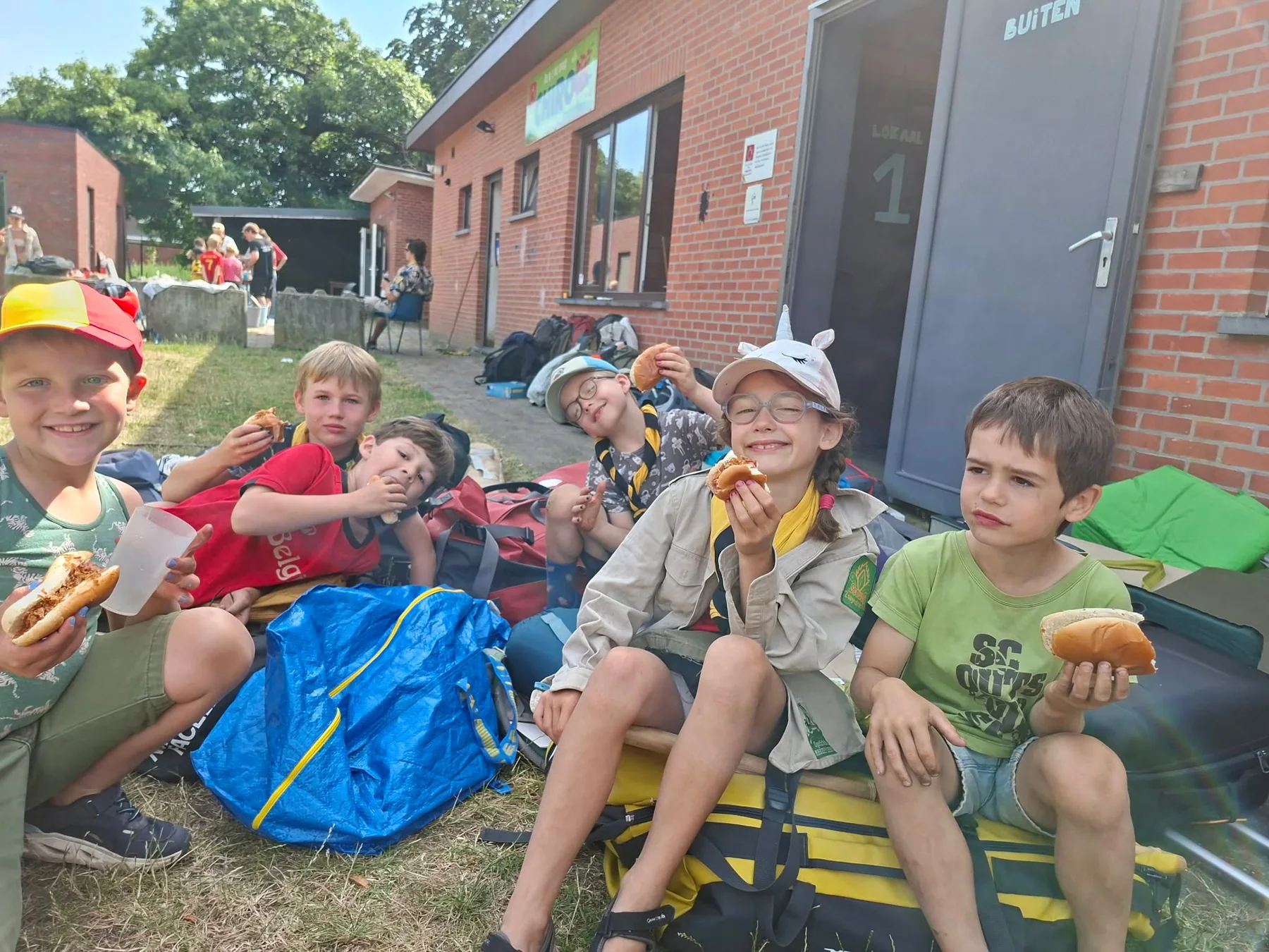 Kapoenen genieten samen van een maaltijd op kamp