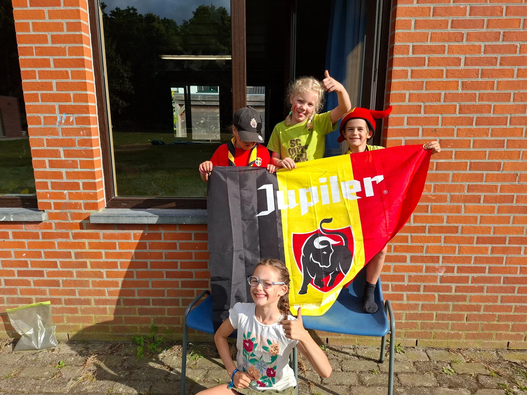 Scoutsleden met een Belgische vlag op het terrein